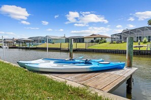 A kayak docked at a wooden pier with a canal and houses in the background. - Intracoastal Waterfront Home | Private Pool, Boat Dock, Screened Lanai, Sleeps 6 (Palm Coast)