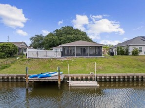 A residential property with a house, a covered porch, and a dock with kayaks. - Intracoastal Waterfront Home | Private Pool, Boat Dock, Screened Lanai, Sleeps 6 (Palm Coast)