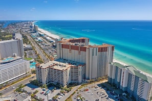 A coastal hotel with multiple buildings, a parking lot, and a beach view. - Beachfront | Gulf & Lagoon Pool Views | Sleeps 8 | Same-Floor Parking (Panama City Beach)