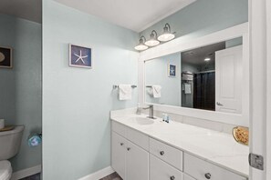 A bathroom with a white vanity, a large mirror, and a starfish decoration on the wall. - Beachfront | Gulf & Lagoon Pool Views | Sleeps 8 | Same-Floor Parking (Panama City Beach)
