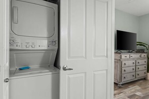 A laundry room with a washing machine, a blue cloth, and a wooden dresser with drawers. - Beachfront | Gulf & Lagoon Pool Views | Sleeps 8 | Same-Floor Parking (Panama City Beach)