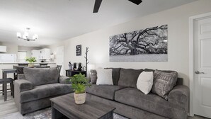 En stue med en modulsofa, et sofabord, en plante og et stort abstrakt billede på væggen.