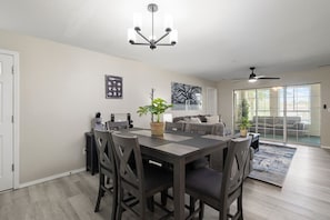 Un espace repas comprenant une table, des chaises, un lustre et un ventilateur de plafond.