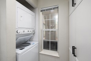 Une buanderie équipée d’un lave-linge et d’un sèche-linge, avec une fenêtre et une porte.