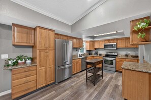 Eine moderne Küche mit Holzschränken, Edelstahlgeräten und einer Arbeitsplatte aus Granit.