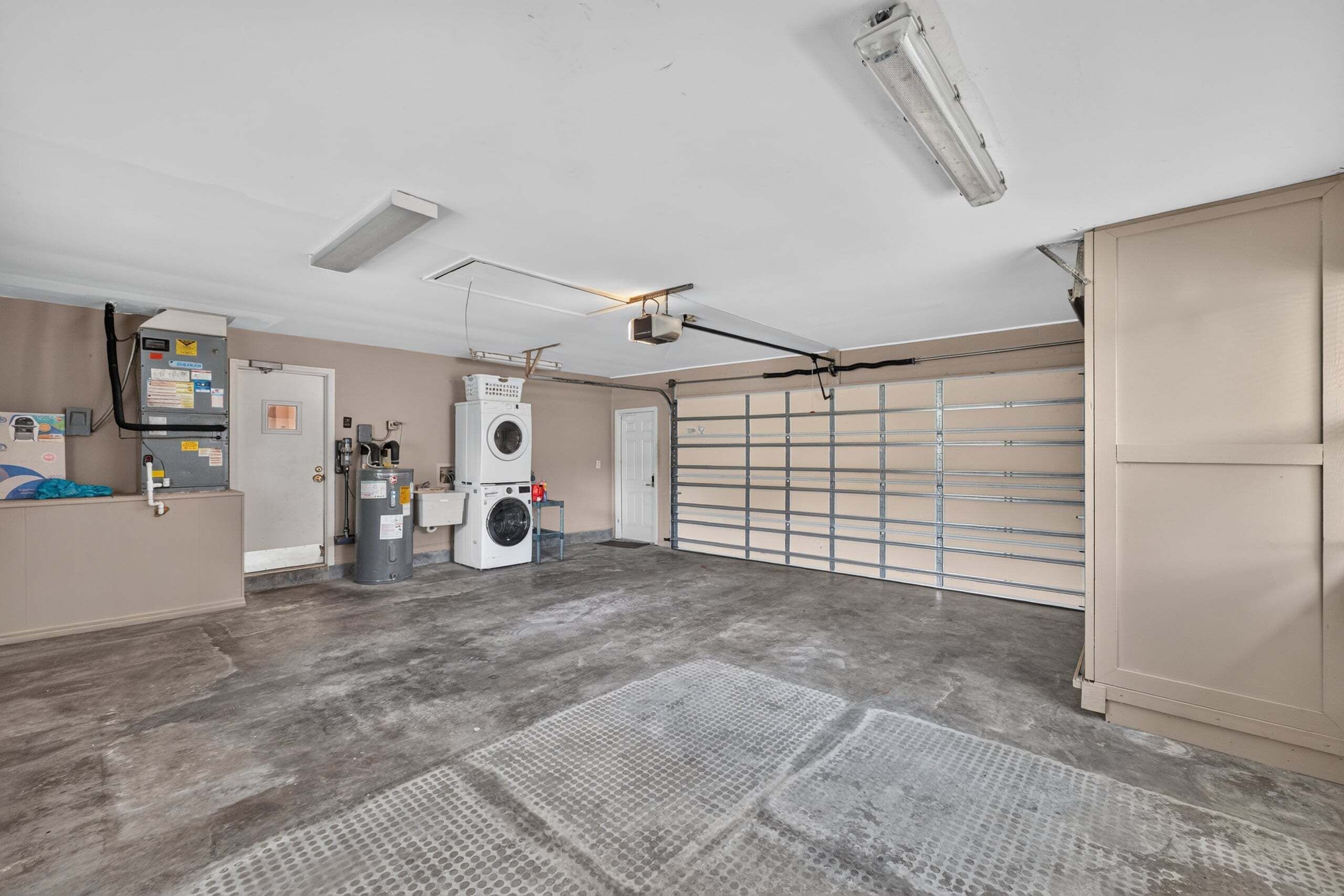 A laundry room with a washing machine, dryer, and a large garage door.