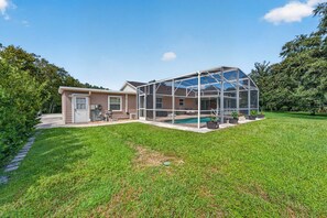 A house with a large glass-enclosed patio area and a swimming pool. - Kissimmee 4BR Poolside Retreat | Private Pool & Sauna (Kissimmee)