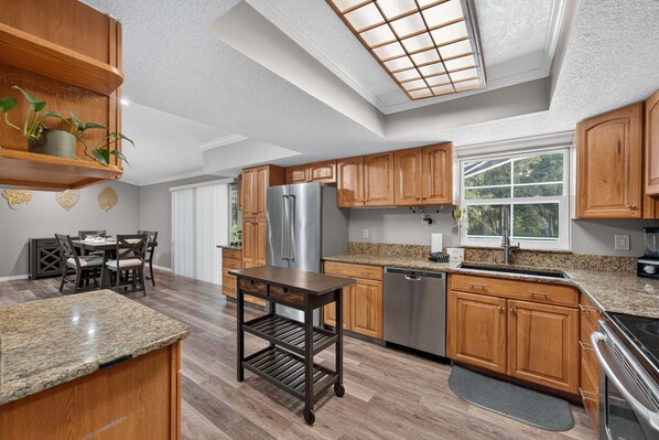 A modern kitchen with wooden cabinets, stainless steel appliances, and a skylight. - Kissimmee 4BR Poolside Retreat | Private Pool & Sauna (Kissimmee)