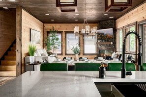 A modern kitchen with a central island, wooden walls, and a fireplace. - Golf Simulator/Rooftop Deck/Hot Tub/3BR/Sleeps 8! (Pigeon Forge)