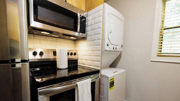 A compact kitchen with a microwave, oven, and a washing machine.
