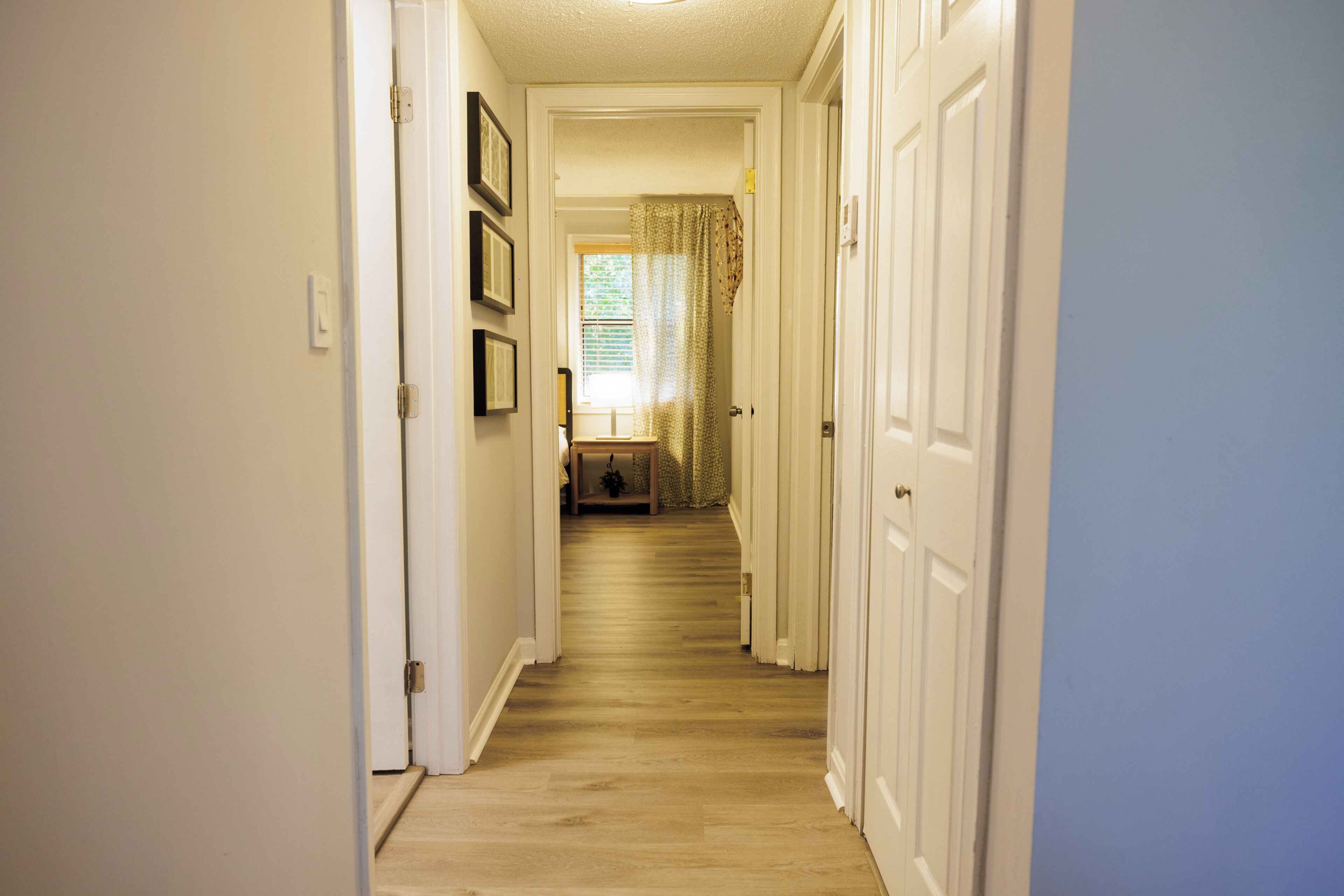 A hallway with wooden flooring, white walls, and doors on both sides.