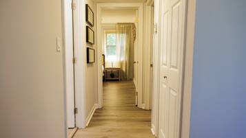 A hallway with wooden flooring, white walls, and doors on both sides.