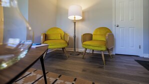 A room with two yellow chairs, a floor lamp, and a white door.
