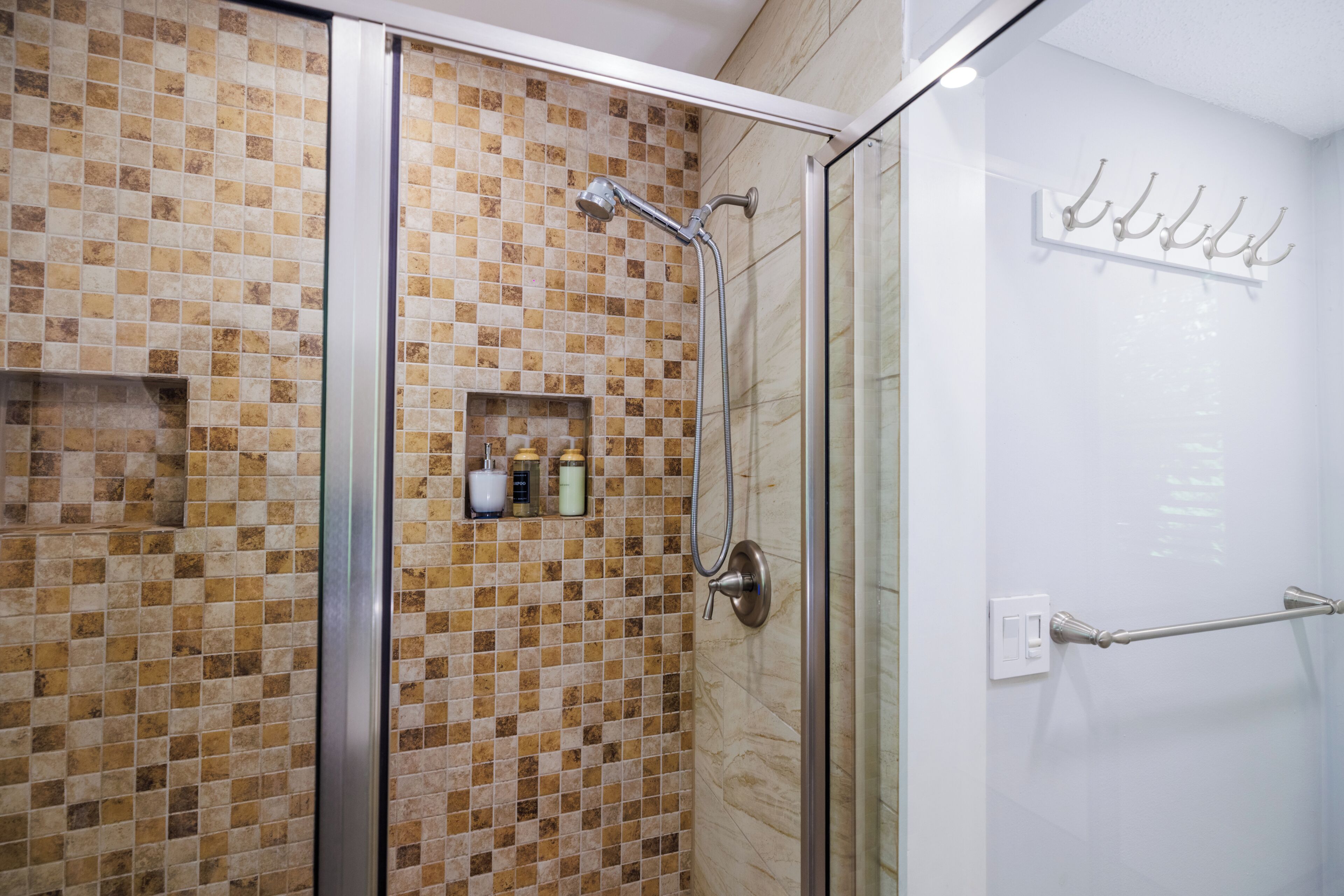 A shower area with a glass door, a tiled wall, and a towel rack.
