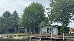 A lakeside cabin with a dock, surrounded by trees. - The Channel House on Lake Winneconne- 3 bedroom 2 bath with boat house game room (Winneconne)