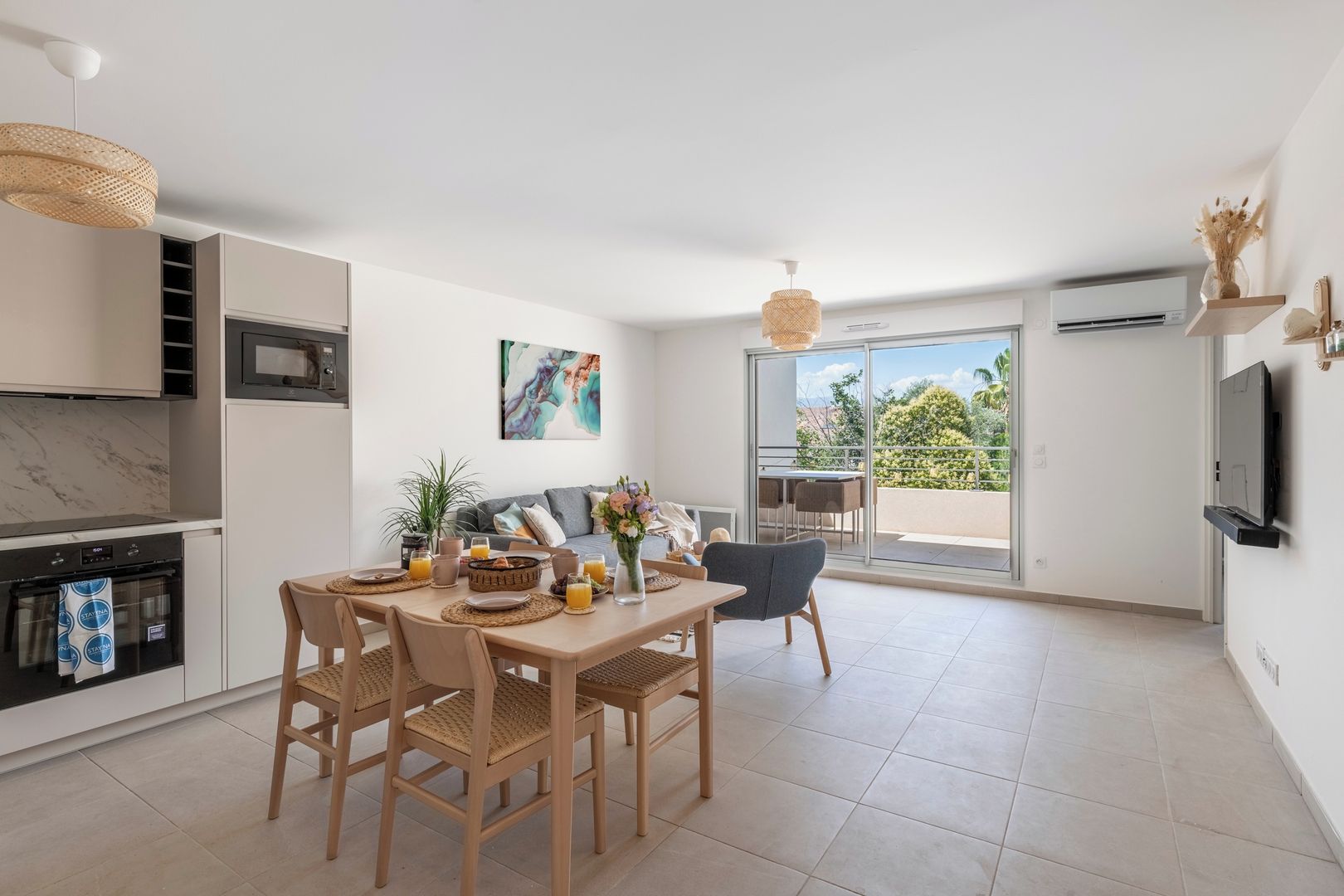 Cozinha moderna com área de refeições, TV e varanda com vista.