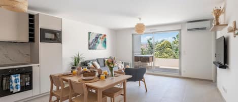 Cozinha moderna com área de refeições, TV e varanda com vista.
