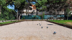 Un patio con césped para croquet, una mesa de picnic y una valla.