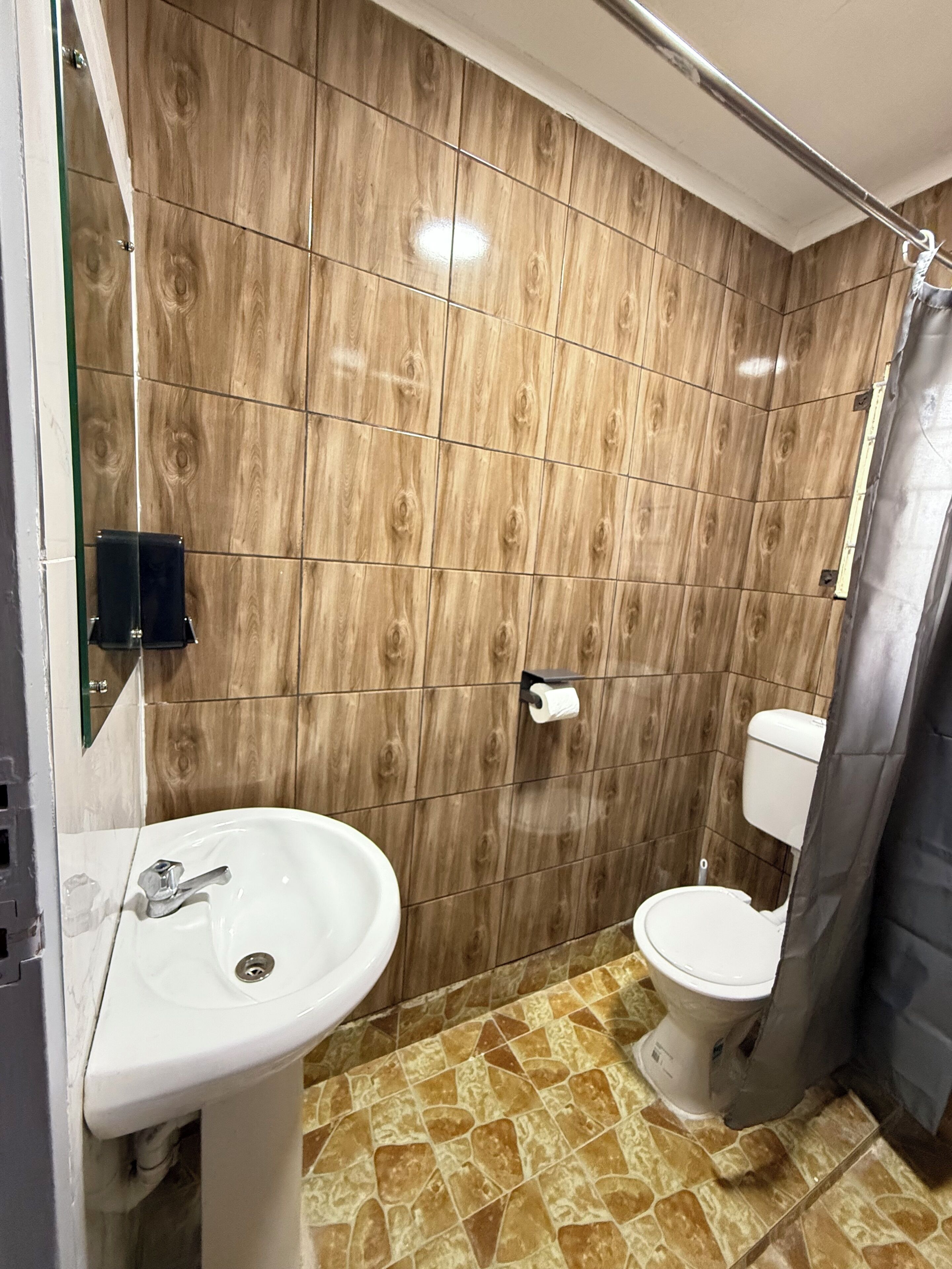 Et badeværelse med håndvask, toilet og bruseforhæng.