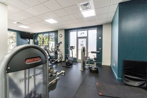 A gym with exercise equipment, a clock on the wall, and large windows. - Oceanfront Penthouse with Pool and Beach Access (Hollywood)