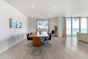 Uma sala de reuniões moderna com uma mesa grande, cadeiras e vista para o mar através de amplas janelas.