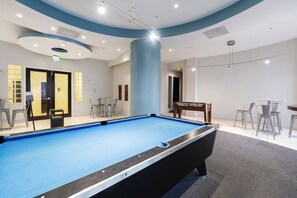 A pool table with surrounding chairs, a table tennis table, and a door with an exit sign. - Oceanfront Penthouse with Pool and Beach Access (Hollywood)