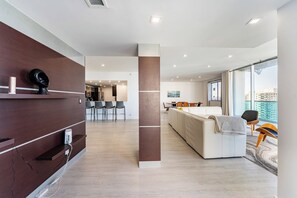 Quarto de hotel moderno com área de estar, espaço para refeições e uma janela grande com vista para a cidade.