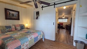A bedroom with a bed, a ceiling fan, a door leading to a hallway, and a painting on the wall. - Remodeled Westgate Cottage Near Pool & Rodeo Fun 316 (River Ranch)