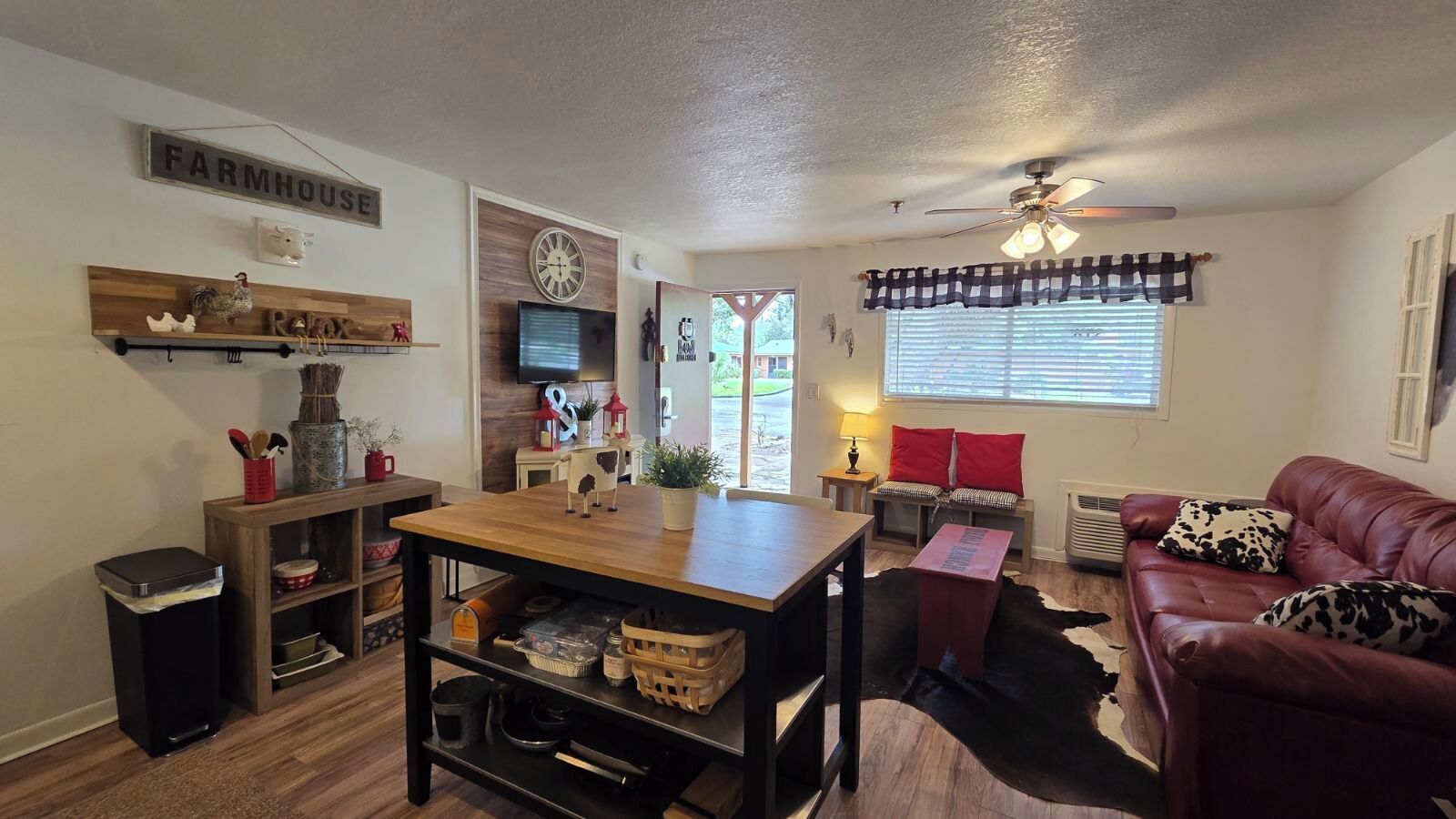 A cozy living room with a wooden table, a leather couch, and a cowhide rug.