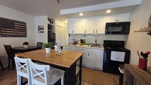 A kitchen with white cabinets, a wooden dining table, and a black stove. - Remodeled Westgate Cottage Near Pool & Rodeo Fun 316 (River Ranch)