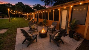 An outdoor patio with a fire pit, four Adirondack chairs, and string lights. - Remodeled Westgate Cottage Near Pool & Rodeo Fun 316 (River Ranch)
