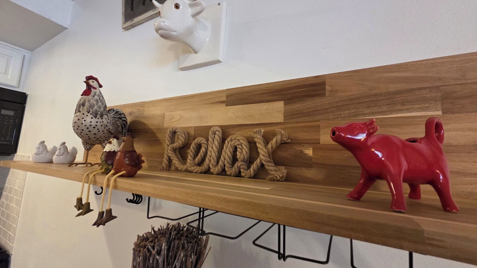 Une étagère en bois ornée de diverses figurines d’animaux et d’une décoration en corde formant le mot « Relax ».