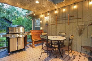 An outdoor patio with a stainless steel grill, wooden chairs, a round table, and a wooden deck. - Fernwood Cabin | Private Hot Tub + Wood-Burning Fire Near Mt Baker (Deming)