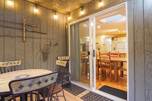 An indoor dining area with a table and chairs, a sliding glass door leading to a kitchen, and wooden paneling on the walls. - Mt Baker Forest Cabin Hot Tub Fireplace (Deming)