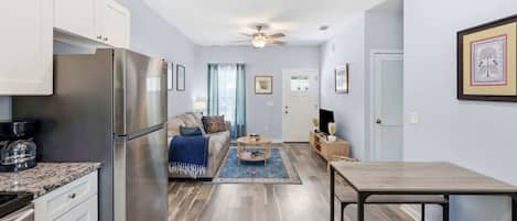 A compact kitchen with a refrigerator, a dining table, and a sofa in the living area.