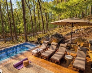 A poolside area with lounge chairs, a small table, and a large umbrella. - 3-bedroom house in peaceful Callicoon perfect for relaxing getaways (Callicoon)