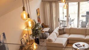 Amplia sala de estar con una mesa de comedor lista para cuatro personas, un sofá y una mesa de centro.