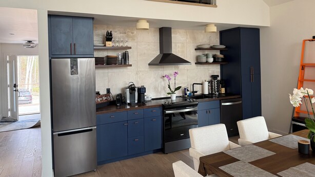Una cocina moderna con horno empotrado, refrigerador y comedor con mesa y sillas.