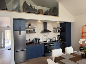 Eine moderne Küche mit Einbauofen, Kühlschrank und Essbereich mit Tisch und Stühlen.