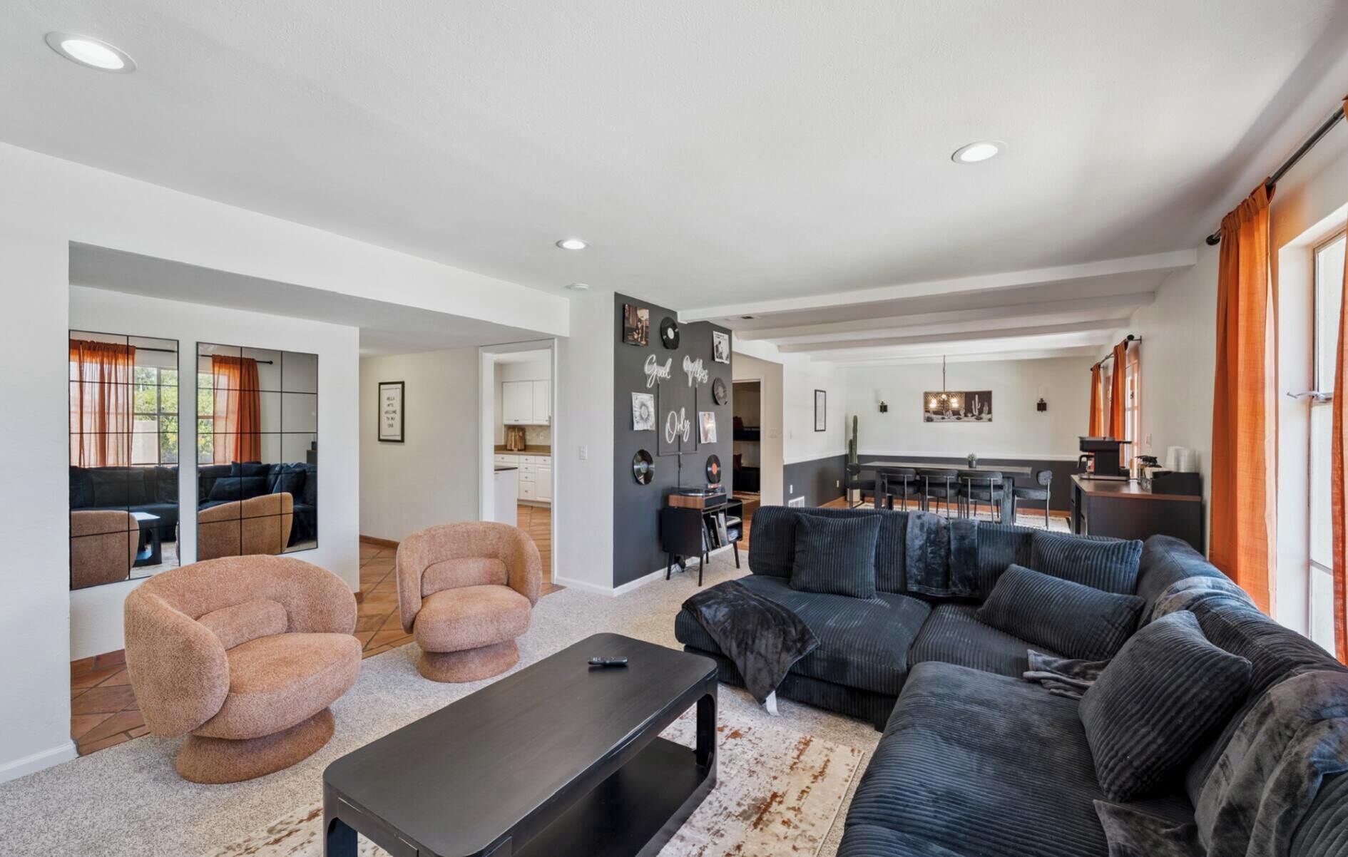 Un amplio espacio de sala con un sofá seccional grande, una mesa de centro y un comedor, con una cocina al fondo.