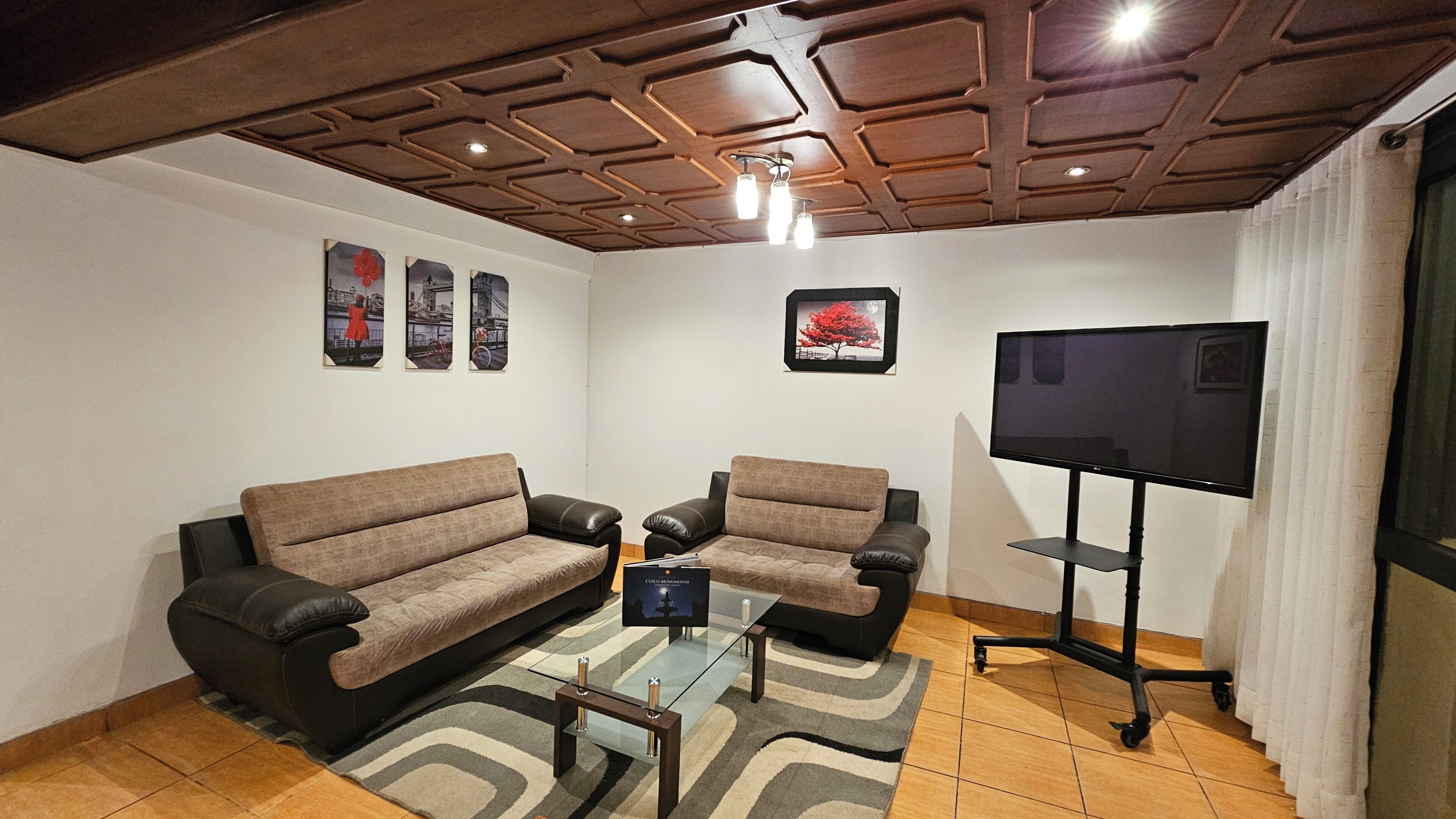 A living room with a sofa, two armchairs, a coffee table, and a flat-screen TV.