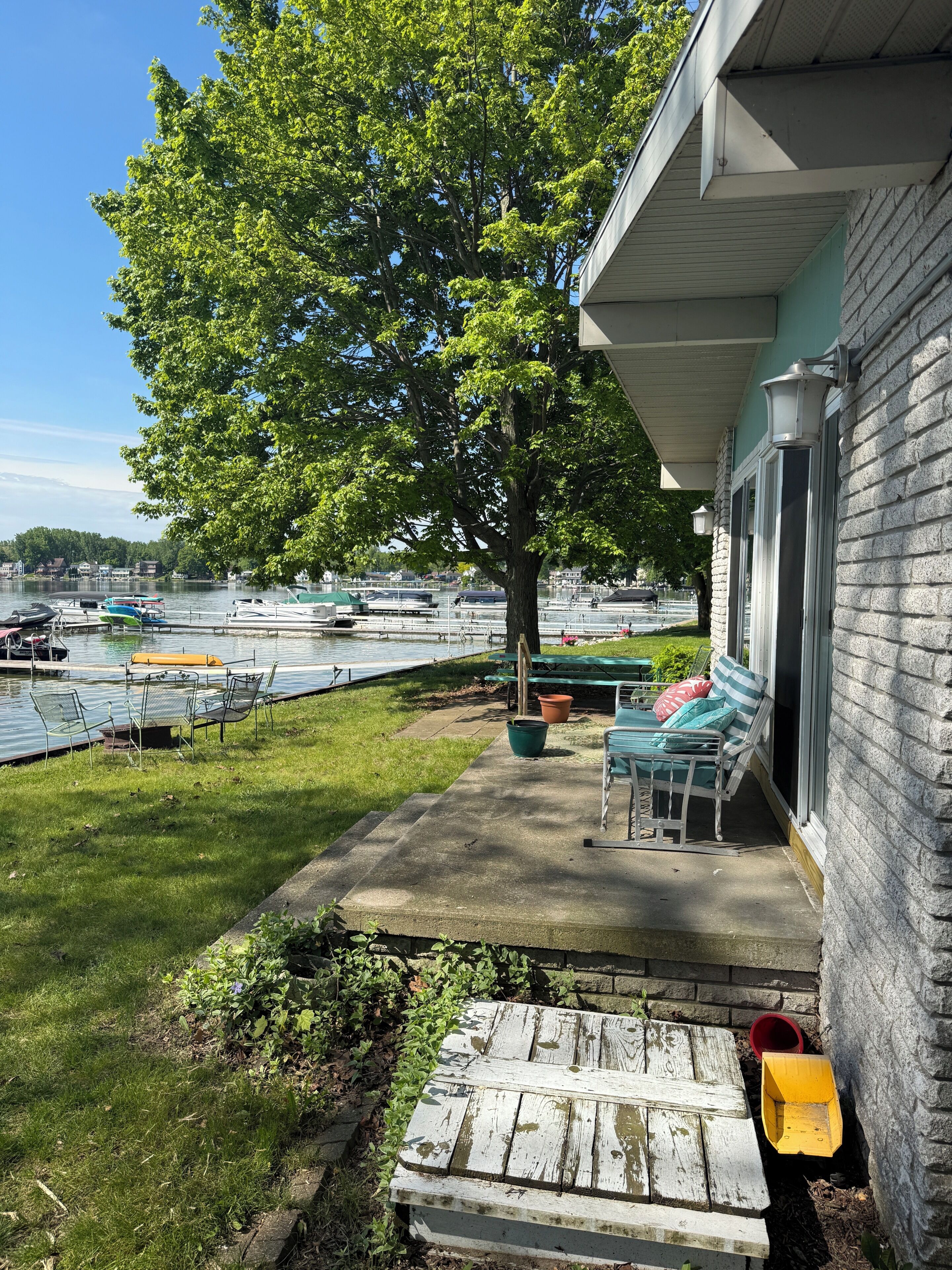 A patio with outdoor seating, a tree, and a view of a marina with boats.