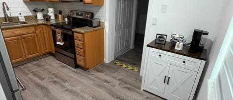 Una cocina moderna con armarios de madera, microondas, horno y cafetera.