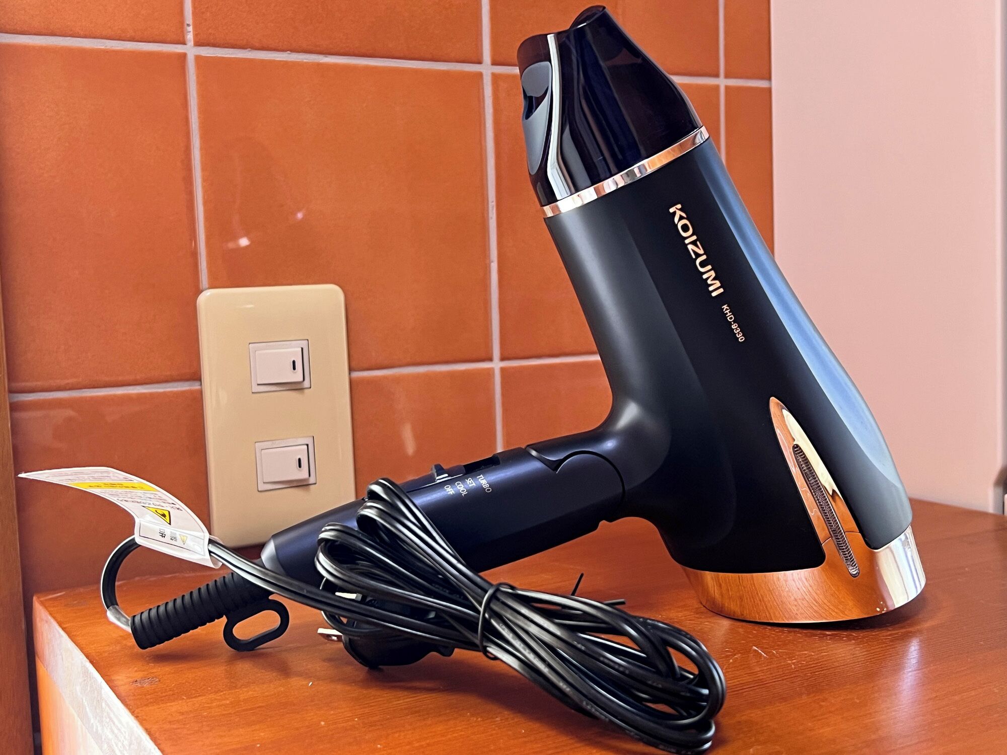A hair dryer with a cord and a power strip on a wooden surface.