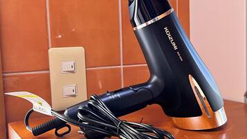 A hair dryer with a cord and a power strip on a wooden surface.