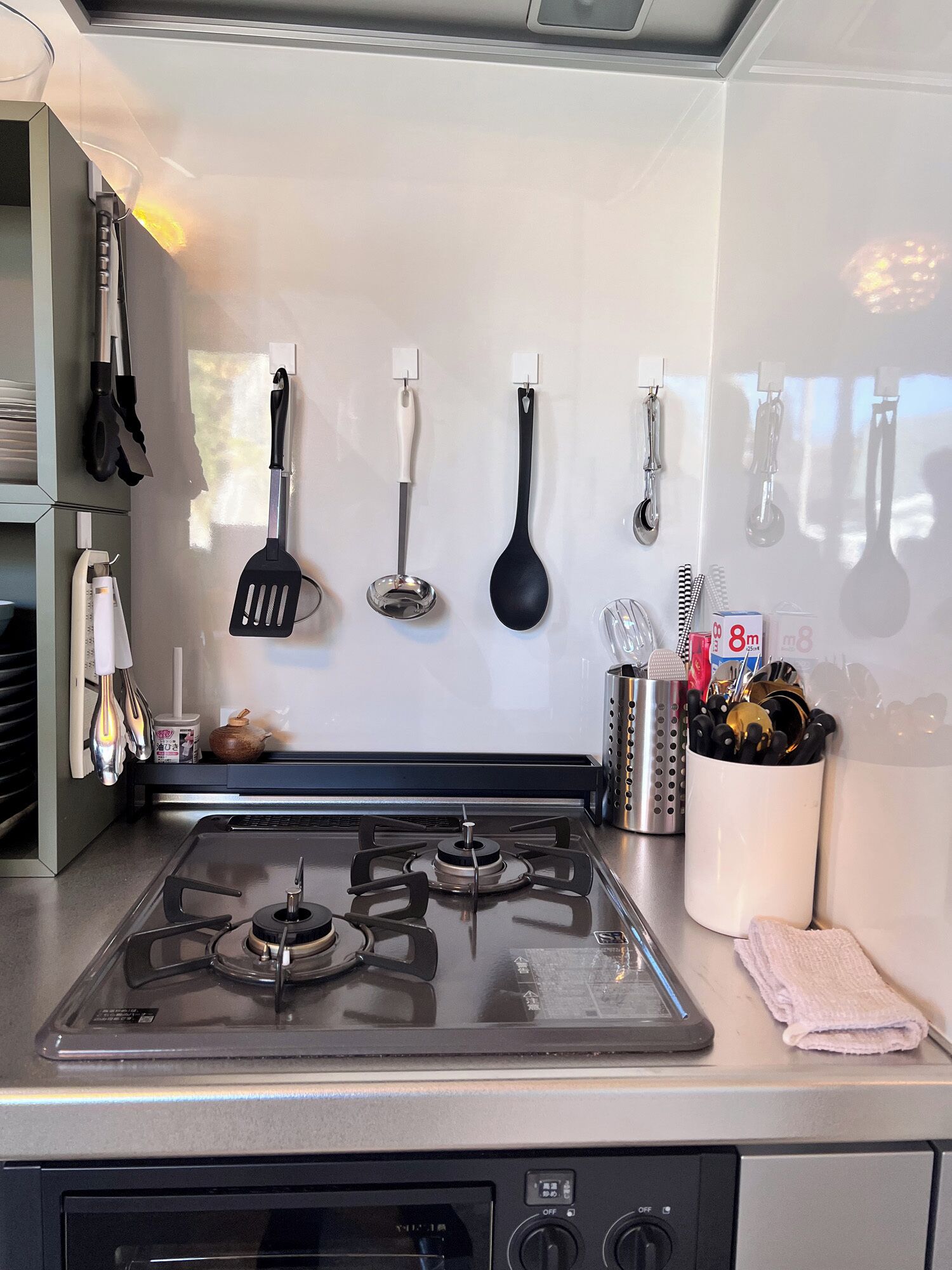 A kitchen with a gas stove, hanging utensils, and a towel on the counter.