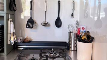 A kitchen with a gas stove, hanging utensils, and a towel on the counter.