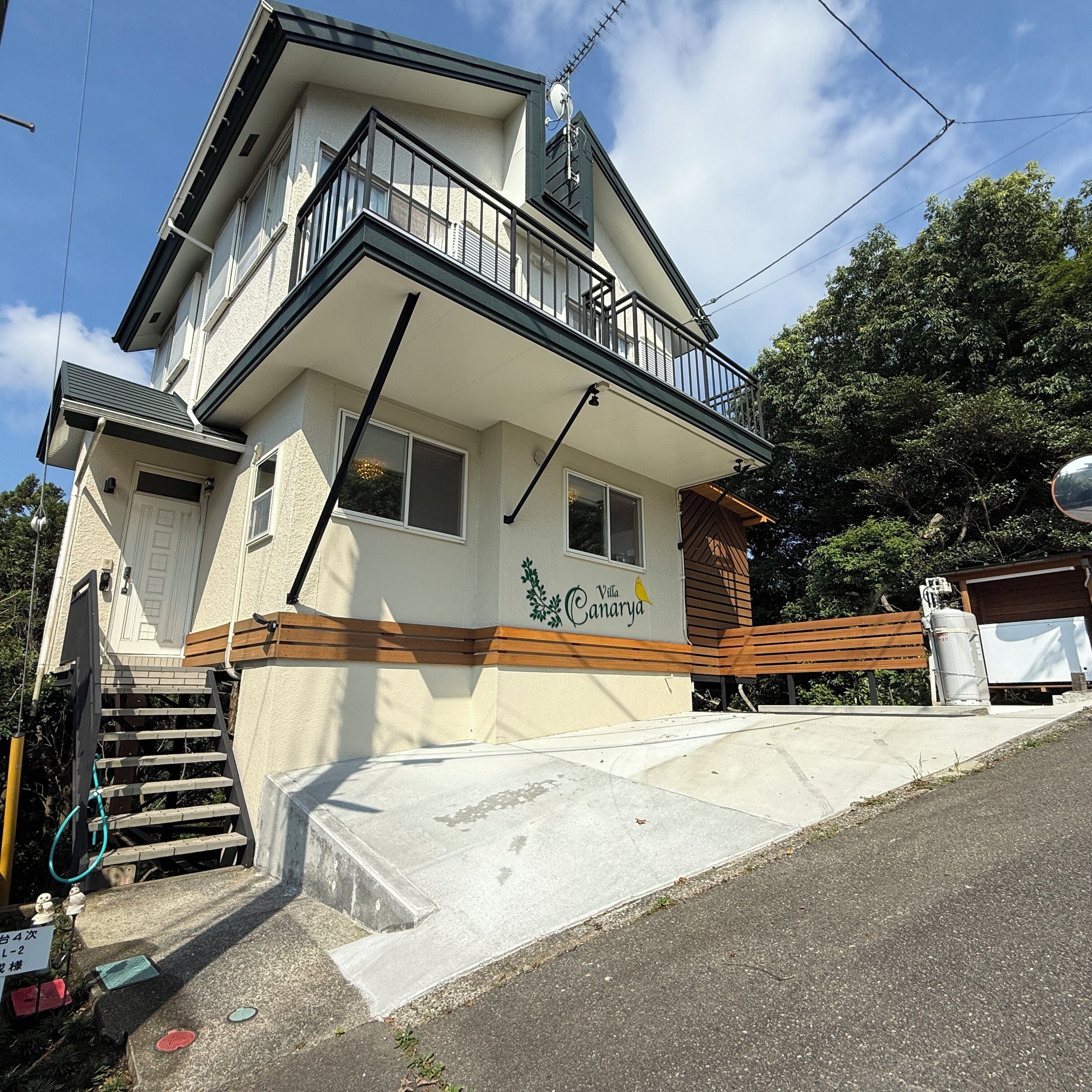 A two-story building with a balcony, a garage, and a small outdoor area with a bench.