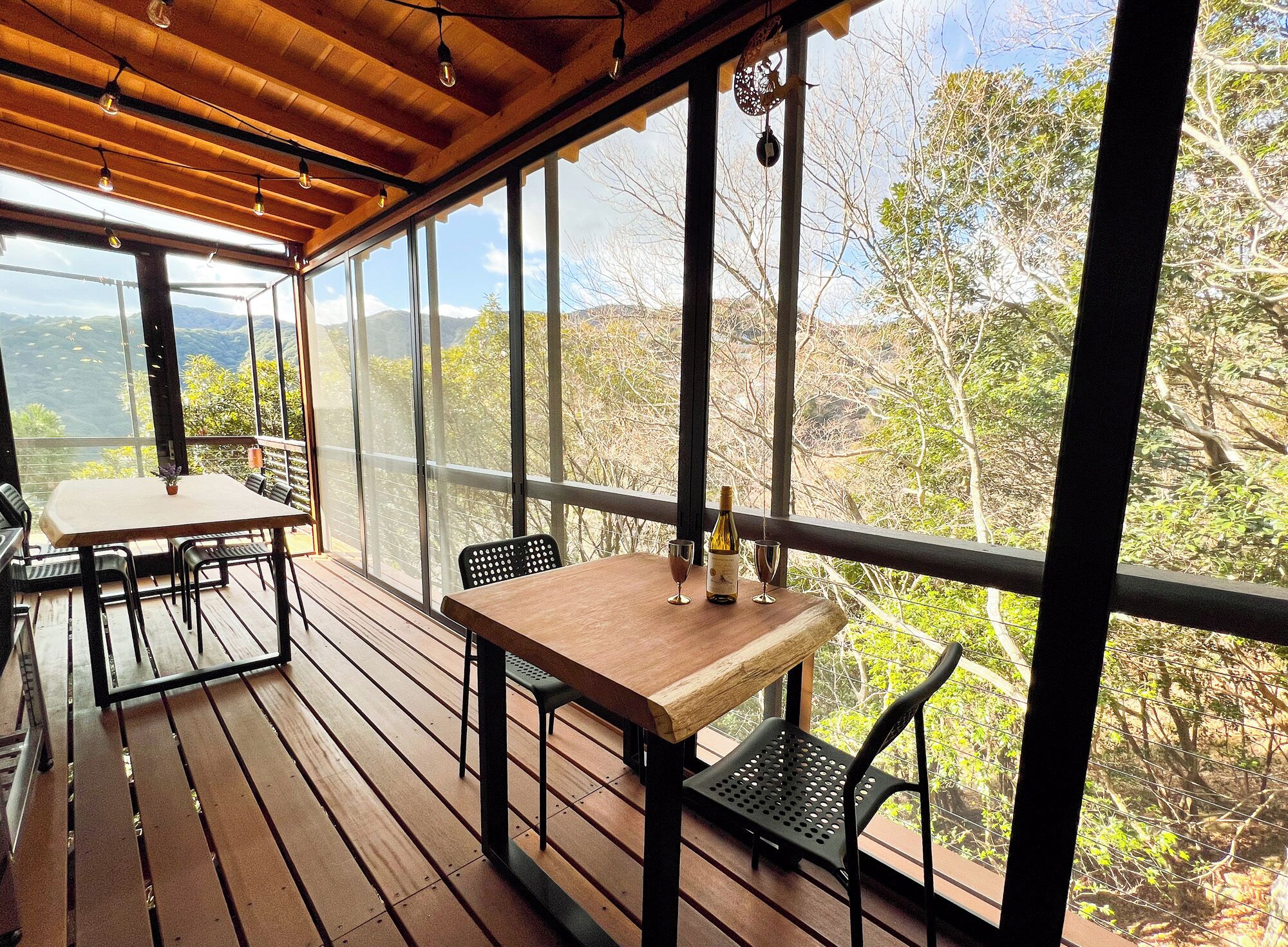 An outdoor patio with wooden flooring, metal chairs, and a table.