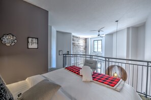 Ein Schlafzimmer mit Bett, Balkon, Deckenventilator und Fenster.